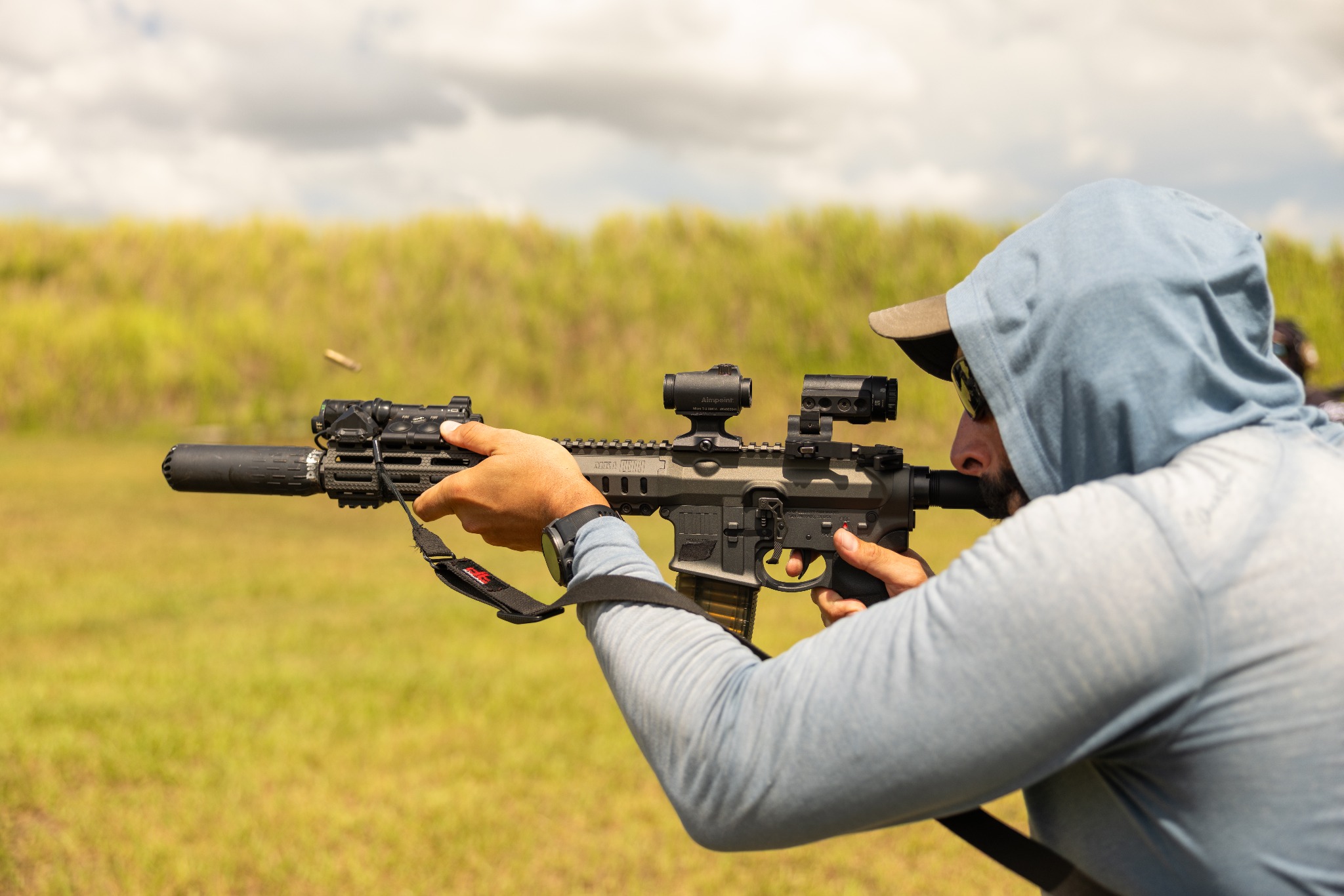 Shooter demonstrating a suppressed rifle at an outdoor Suppressor Supply Co. range event.